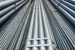 Bundled steel pipes secured with heavy-duty steel strapping in an industrial warehouse, showing the strength and stability needed for shipping heavy materials.
